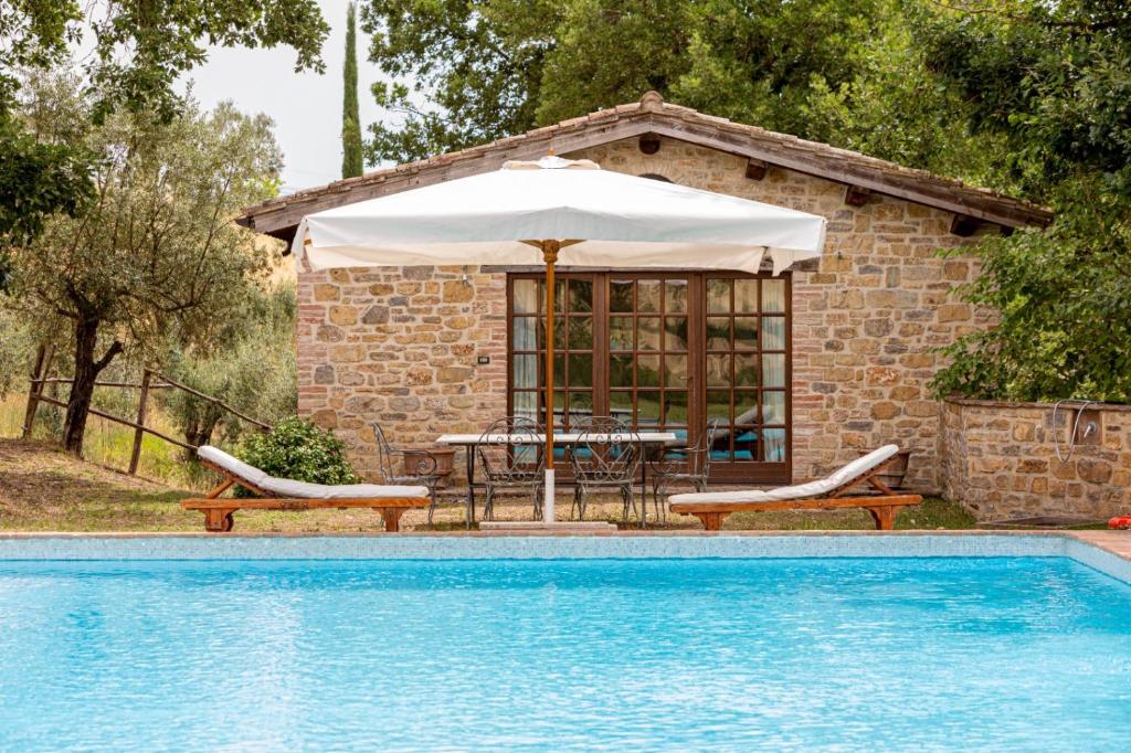 a house with a table and an umbrella next to a pool at Villa Dante - Homelike Villas in Perugia
