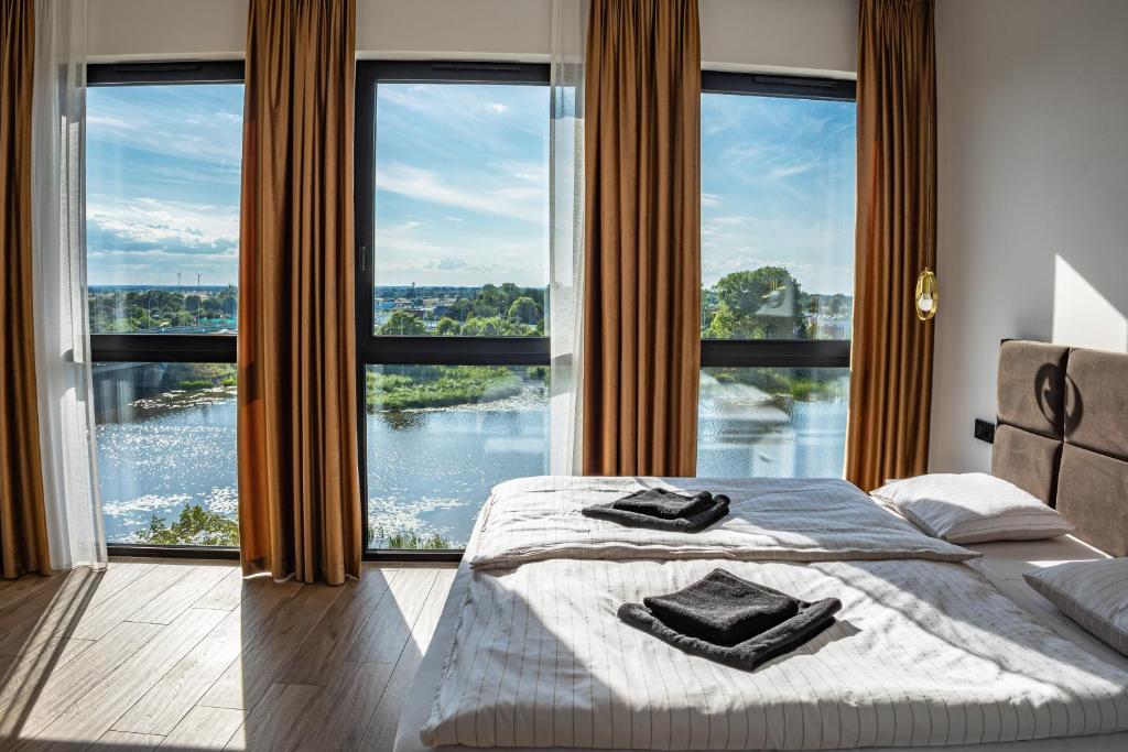 a bedroom with a bed and large windows at Spichlerz Malbork in Malbork