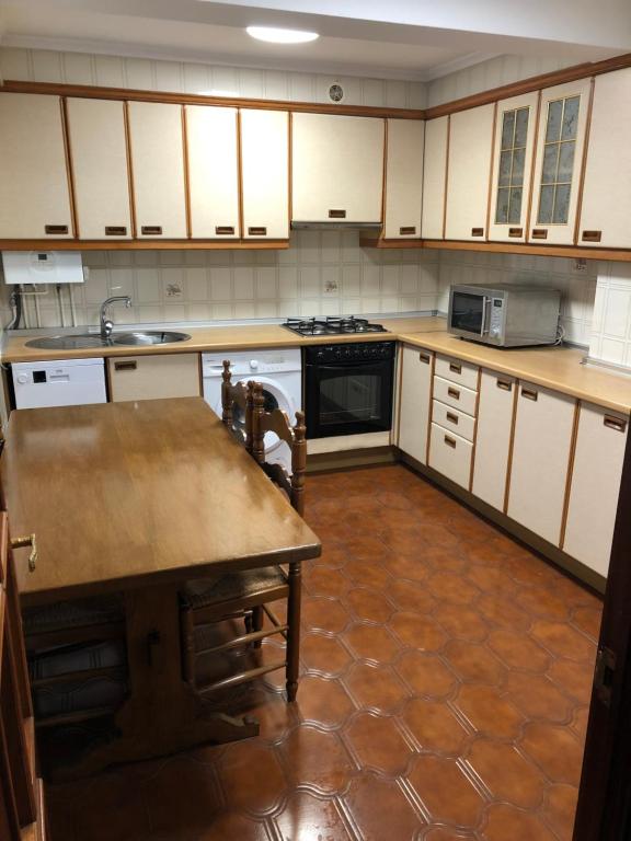 a kitchen with white cabinets and a wooden table at Piso centrico en Irun in Irún