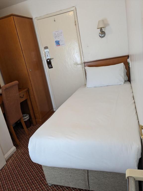 a small bedroom with a white bed in a room at The Tudor Hotel in Harrow