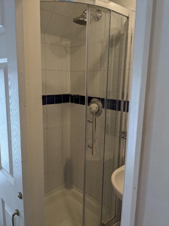 a shower with a glass door next to a sink at The Tudor Hotel in Harrow