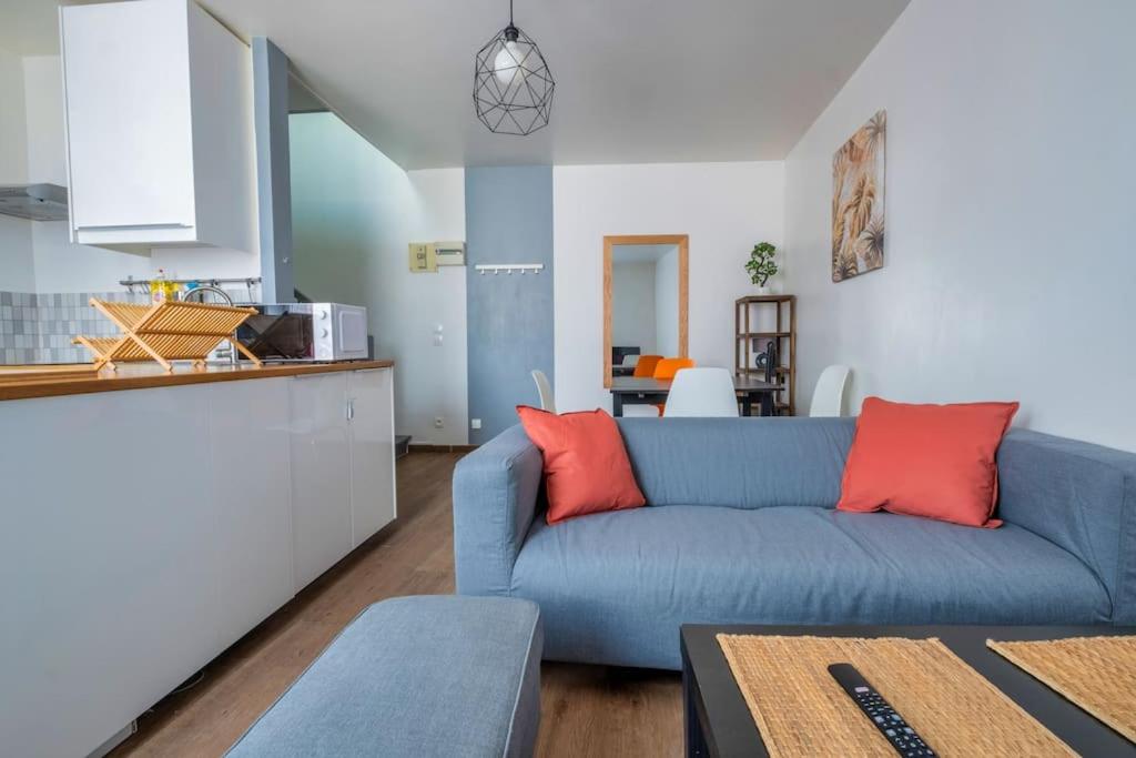 un salon avec un canapé bleu et une cuisine dans l'établissement Volcano, à Reims