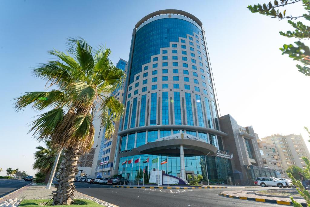 a tall blue building with a palm tree in front of it at Grand Hotel in Kuwait