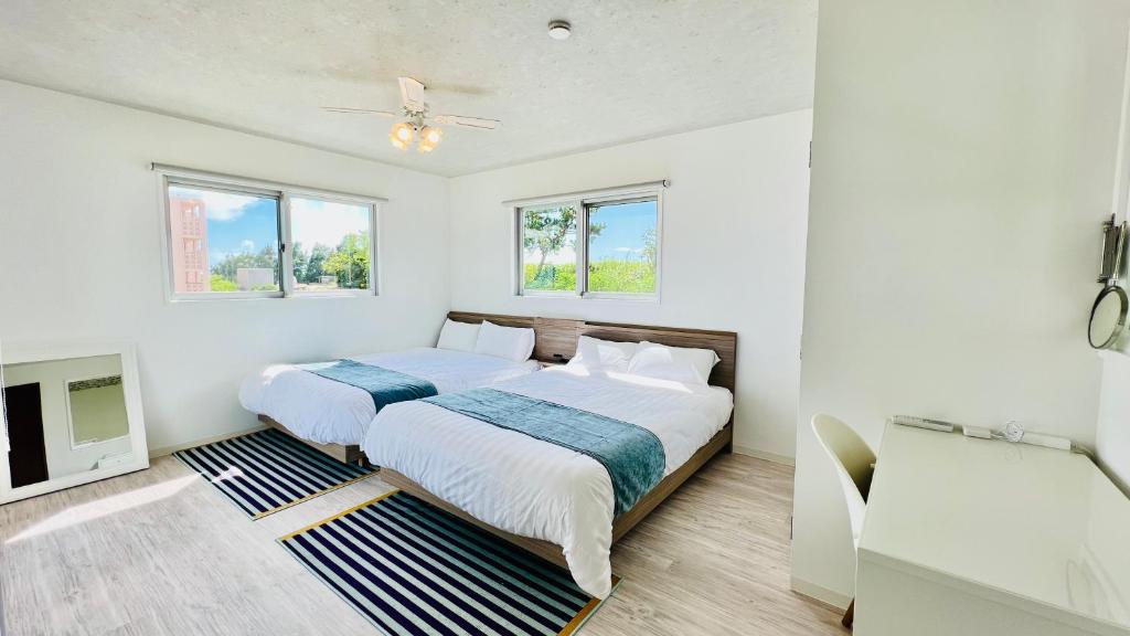 ein weißes Schlafzimmer mit 2 Betten und einem TV in der Unterkunft Miyako Blue Villa Kugai in Miyako-jima