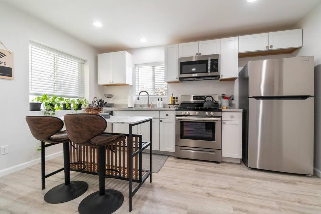 una cocina con armarios blancos y electrodomésticos de acero inoxidable en Urban Oasis: San Diego Bungalow Escape en San Diego