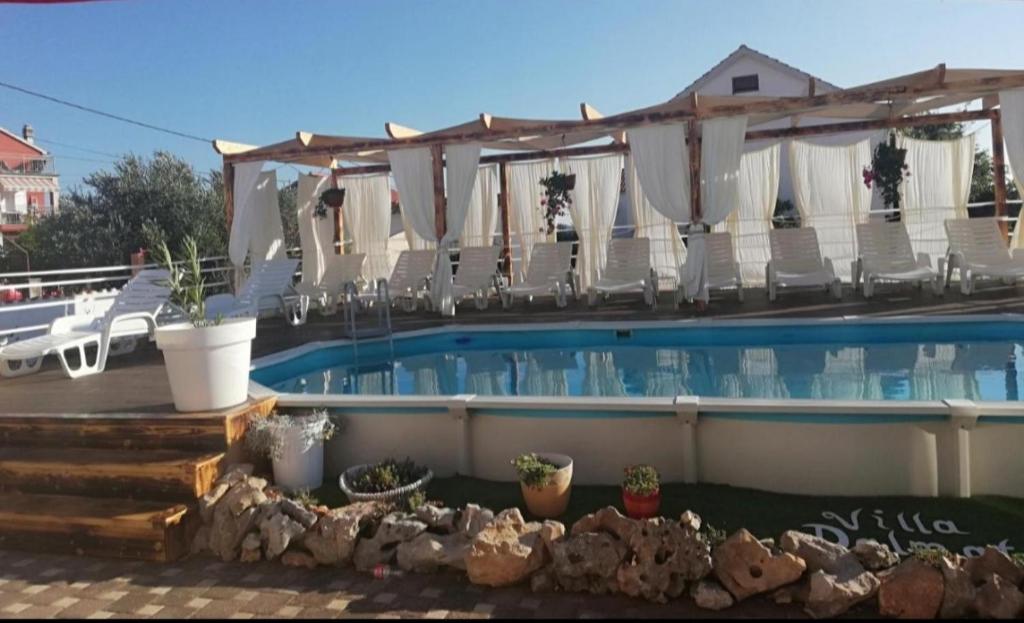 un hotel con una piscina con sillas blancas en Apartments Villa Dalmatina, en Vodice