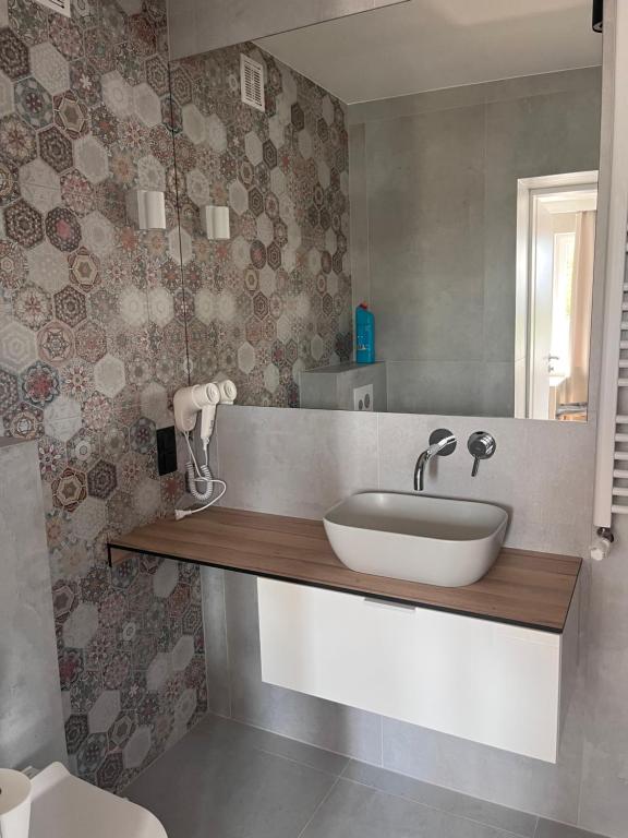 Bathroom vanity with white oval sink, hexagonal patterned tiled wall and mounted hairdryer.