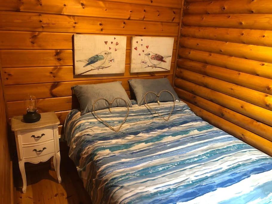 Cama en habitación con pared de madera en Cabaña de ensueño en el bosque y junto al mar, en Miengo