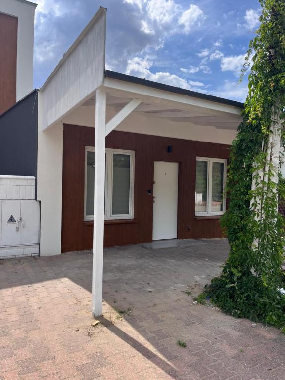 Front porch with white support post, brown wooden facade, door and climbing ivy.
