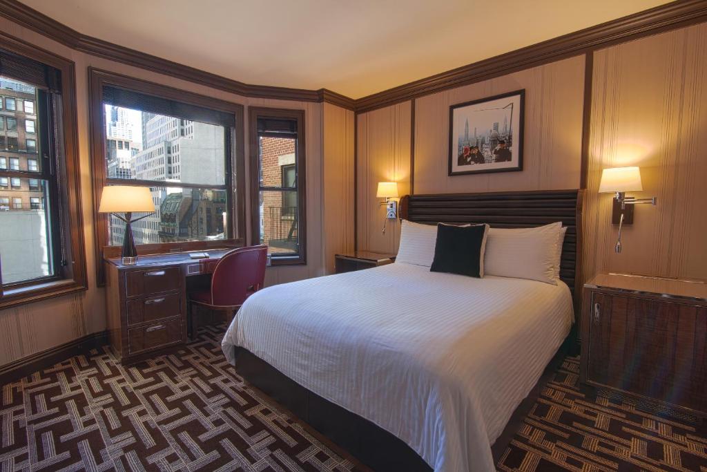 a hotel room with a bed and a desk and window at Iroquois New York Times Square in New York