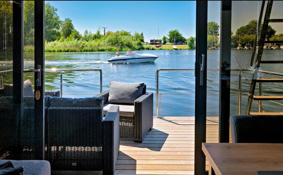 a boat on a river with a boat on the water at Hausboot La Mare Seeblick in Weyhe