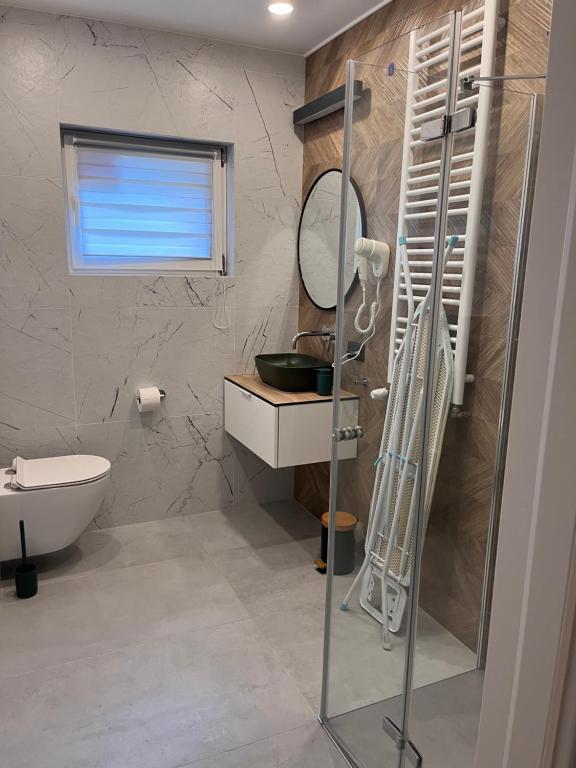 Contemporary bathroom with glass shower, wall-mounted radiator, floating vanity and folded ironing board.