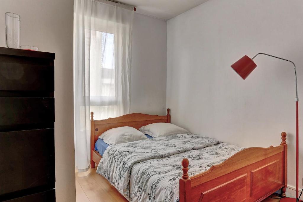 a bedroom with a bed and a lamp and a window at Le Charlemagne- Boulogne in Boulogne-Billancourt