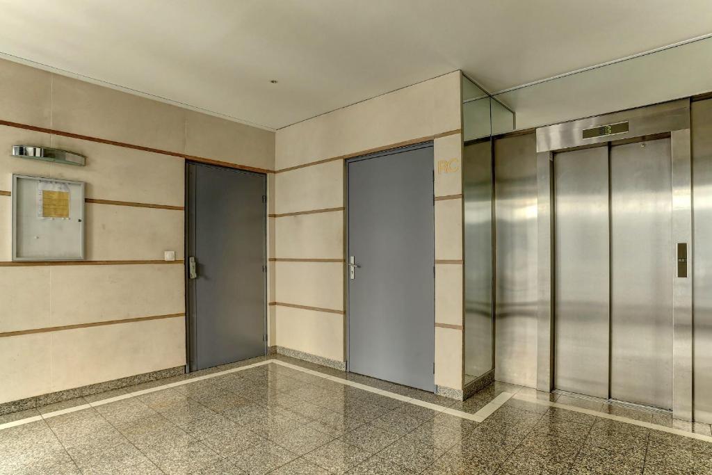 a hallway with three elevators in a building at Le Charlemagne- Boulogne in Boulogne-Billancourt