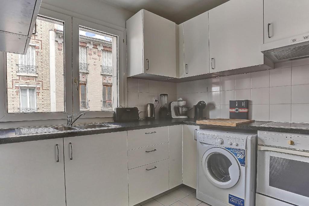 a white kitchen with a washing machine in it at Le Charlemagne- Boulogne in Boulogne-Billancourt