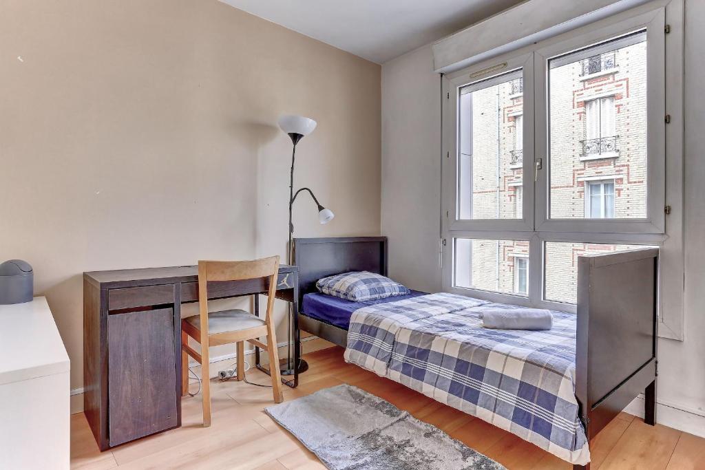 a bedroom with a bed and a desk and a window at Le Charlemagne- Boulogne in Boulogne-Billancourt