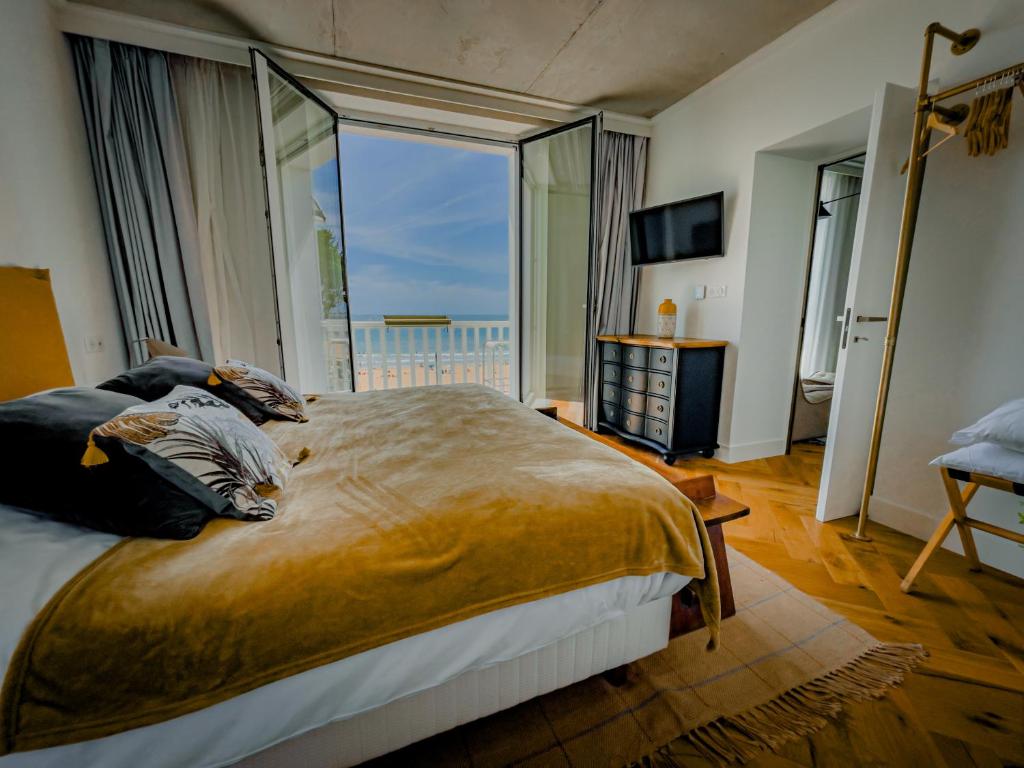 a bedroom with a large bed with a large window at La Maison Régent & spa face à la mer in Pornichet