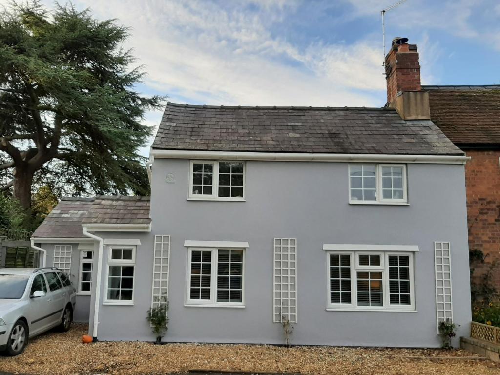 a white house with a car parked in front at Clematis Cottage in Shrewsbury