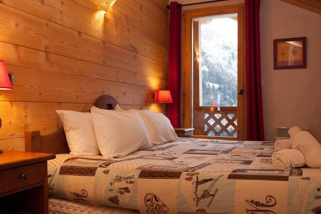 a bedroom with a bed with a wooden wall at L&#39;Aiglon - spacious 2-bedroom apartment with log fire in Sainte-Foy-Tarentaise