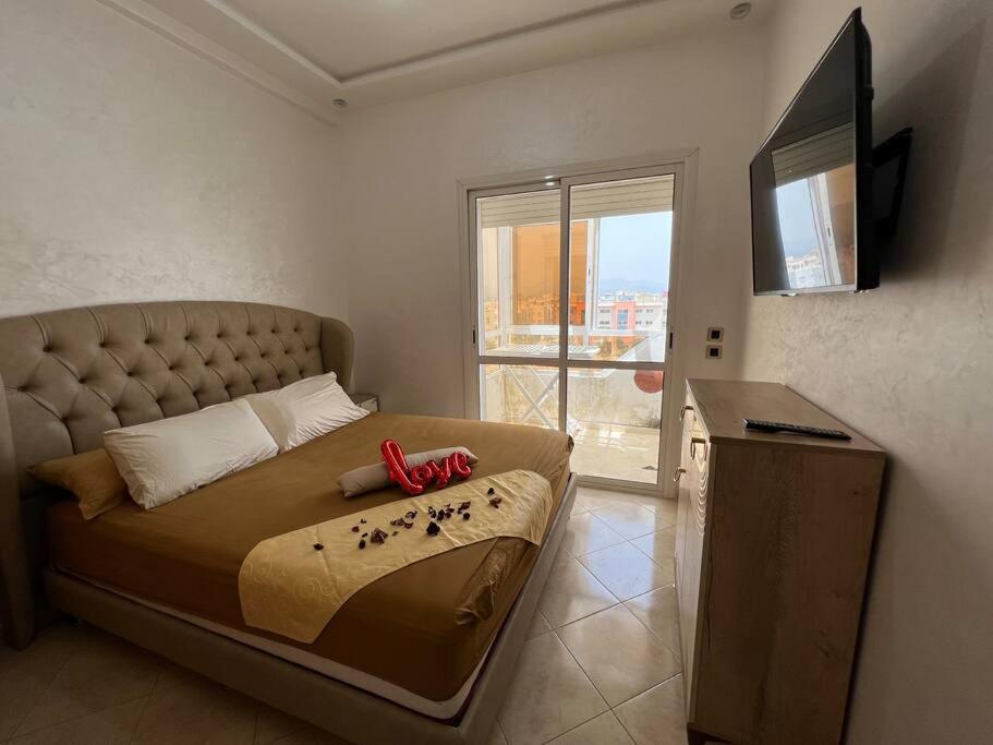 een slaapkamer met een groot bed en een televisie bij Appartement a louer martil in Martil