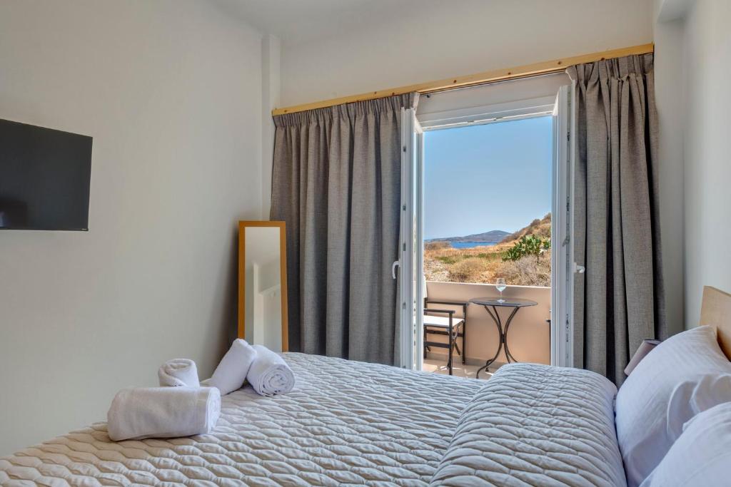 a bedroom with a bed and a large window with a view at Aegean Glory Suites in Ermoupoli