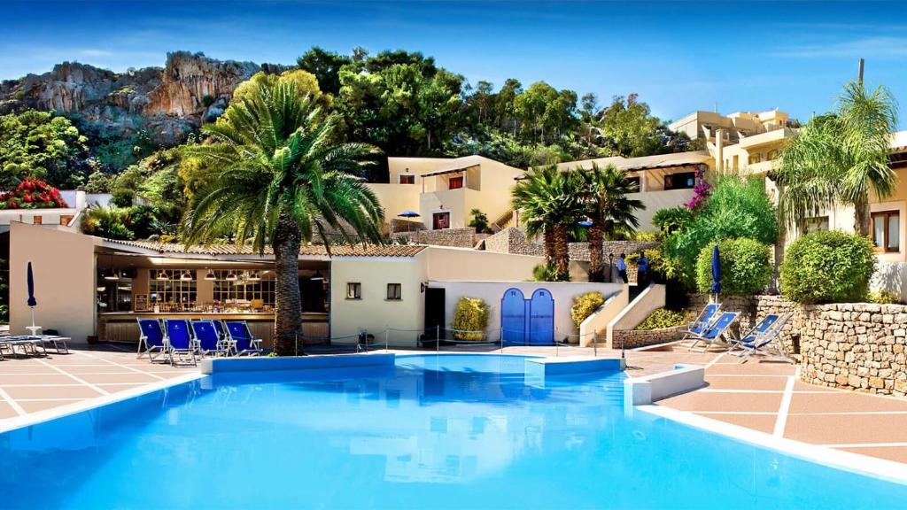 una piscina frente a una casa con palmeras en Appartamento villaggio Calamancina San Vito Lo Capo, en San Vito lo Capo