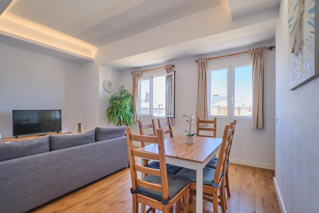 ein Wohnzimmer mit einem Sofa, einem Tisch und Stühlen in der Unterkunft Apartments Vegueta Suite in Las Palmas de Gran Canaria