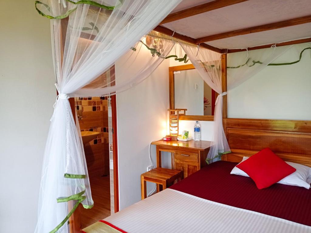 a bedroom with a bed with a red and white canopy at Rainforest Nest in Deniyaya