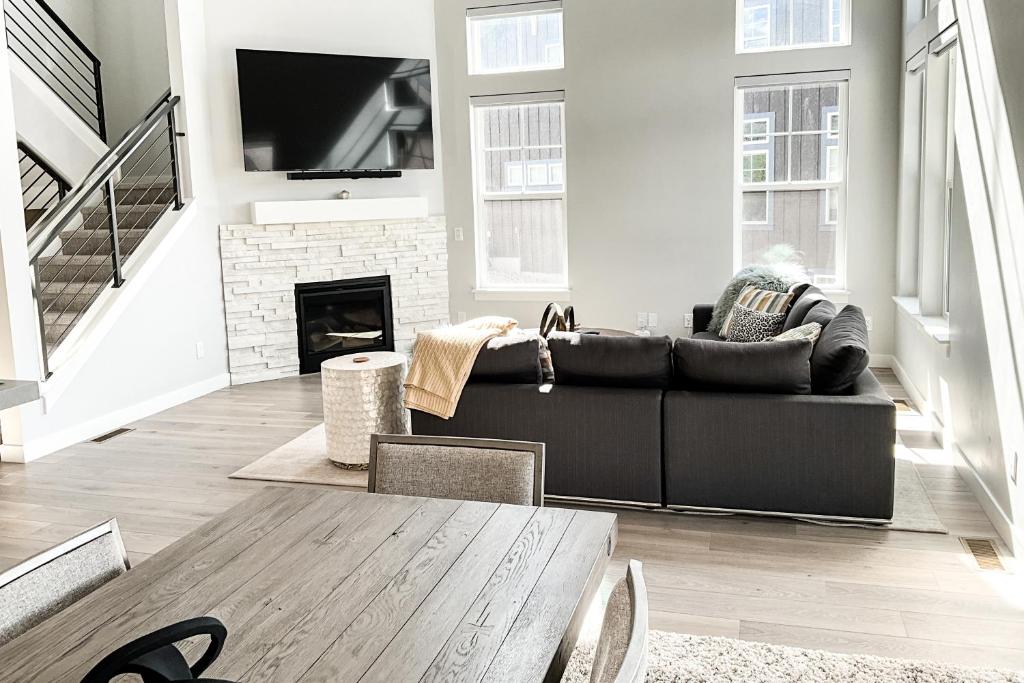 a living room with a black couch and a fireplace at Modern Mountain Retreat in Keetley