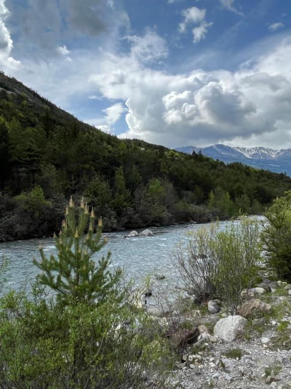 une rivière avec des arbres et des montagnes en arrière-plan dans l'établissement En pleine nature avec jardin, à Les Blancs