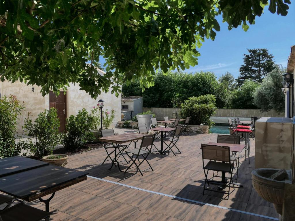 a patio with tables and chairs under a tree at Coeur de Provences in Saint-Didier