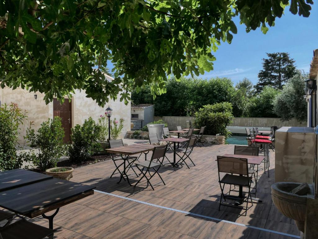 un patio con mesas y sillas bajo un árbol en Coeur de Provences, en Saint-Didier