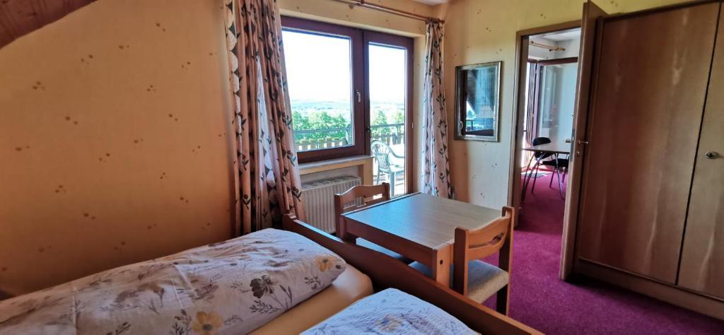 a room with a bed and a table and a window at Apartment mit Balkon in Kempfeld