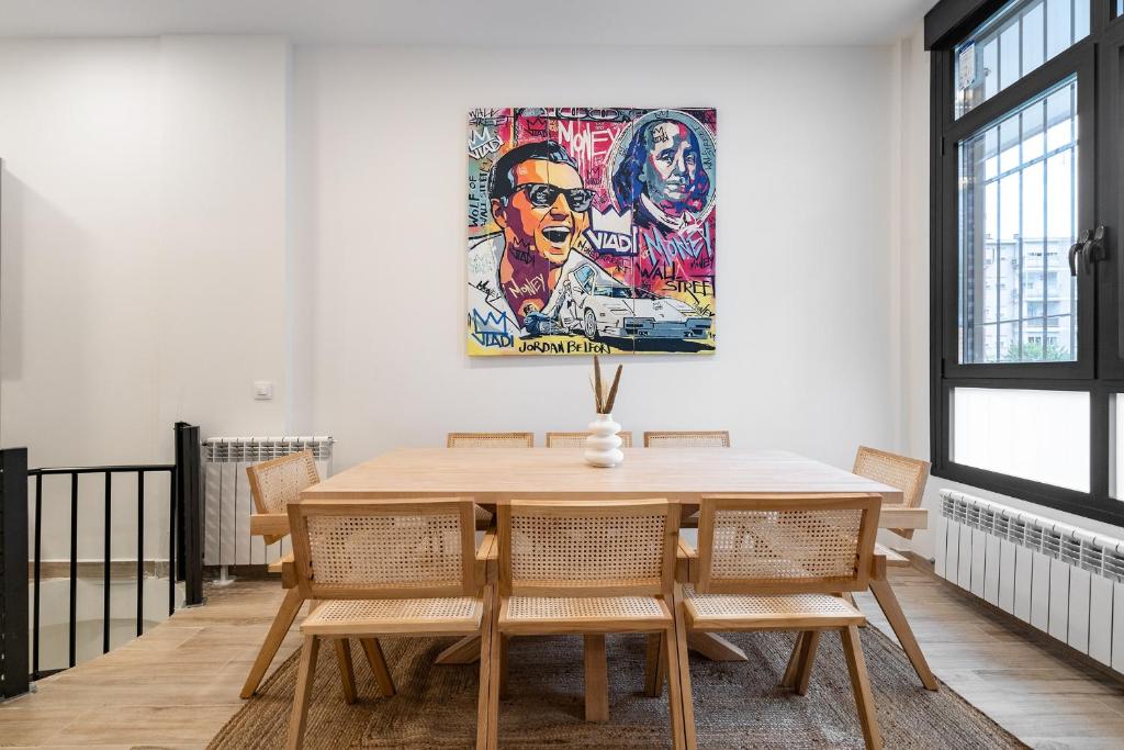 un comedor con mesa, sillas y una pintura en amplio duplex reformado, en Madrid