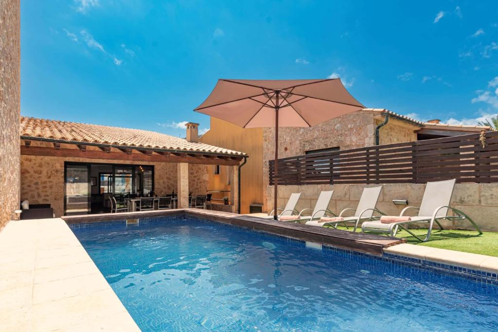 a swimming pool with chairs and an umbrella at Villa Nogues in Cala de Sant Vicenc