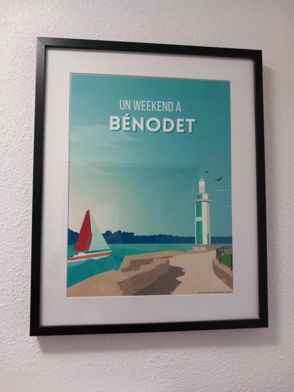 a framed picture of a beach with a boat and a lighthouse at le loft de la riviéra in Bénodet
