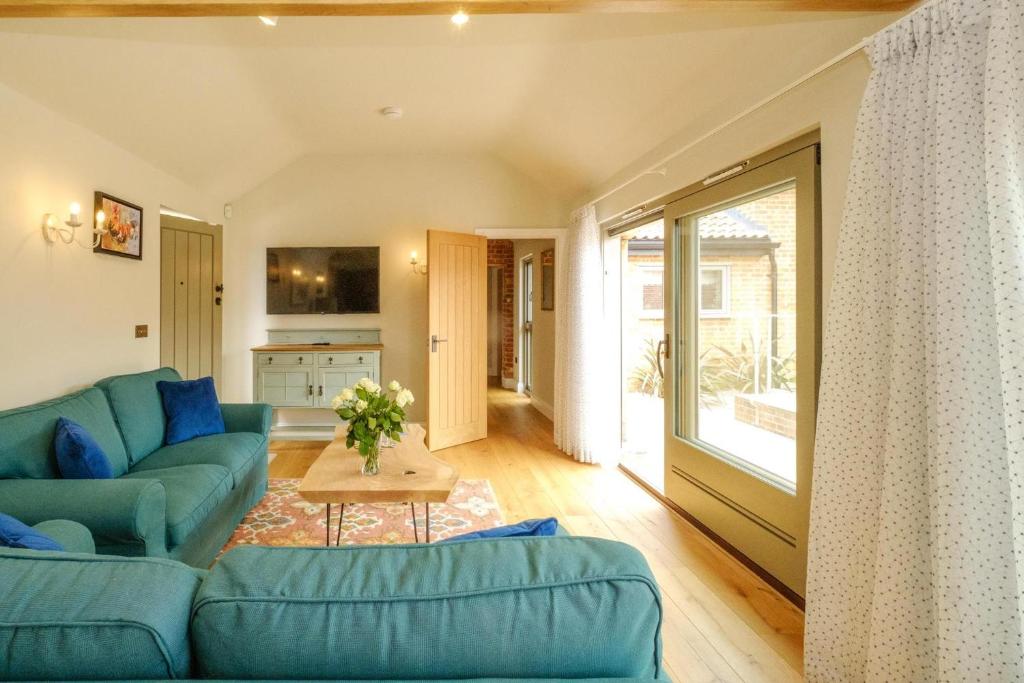 a living room with a blue couch and a table at Alde Bay Farm - Oyster Catcher in Aldeburgh