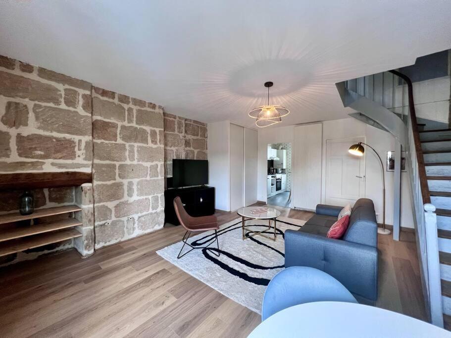a living room with a blue couch and a stone wall at Élégante &amp; Design Casa Churchill - Brive Centre in Brive-la-Gaillarde
