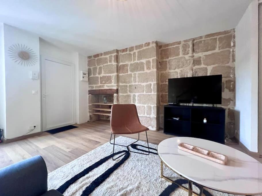 a living room with a table and a brick wall at Élégante &amp; Design Casa Churchill - Brive Centre in Brive-la-Gaillarde