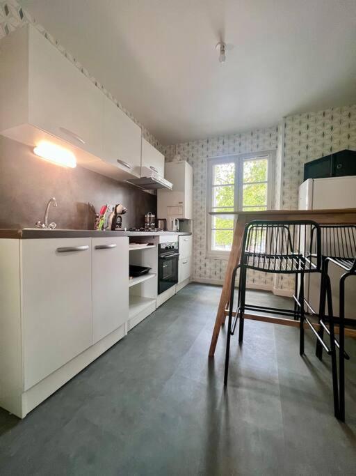 a kitchen with white cabinets and a table and chairs at Élégante &amp; Design Casa Churchill - Brive Centre in Brive-la-Gaillarde