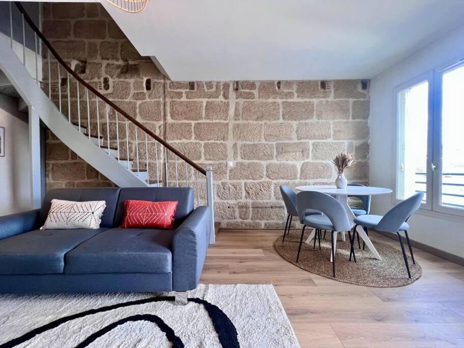 a living room with a blue couch and a brick wall at Élégante &amp; Design Casa Churchill - Brive Centre in Brive-la-Gaillarde