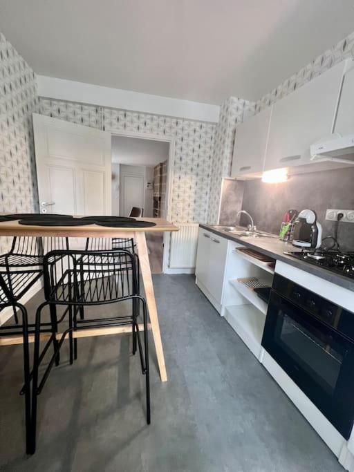 a kitchen with white cabinets and black chairs in it at Élégante &amp; Design Casa Churchill - Brive Centre in Brive-la-Gaillarde