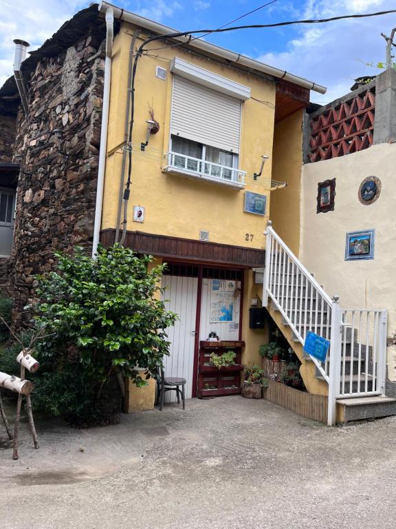 une maison jaune avec une porte blanche et des escaliers dans l'établissement A casa do teléfono, à Pumares