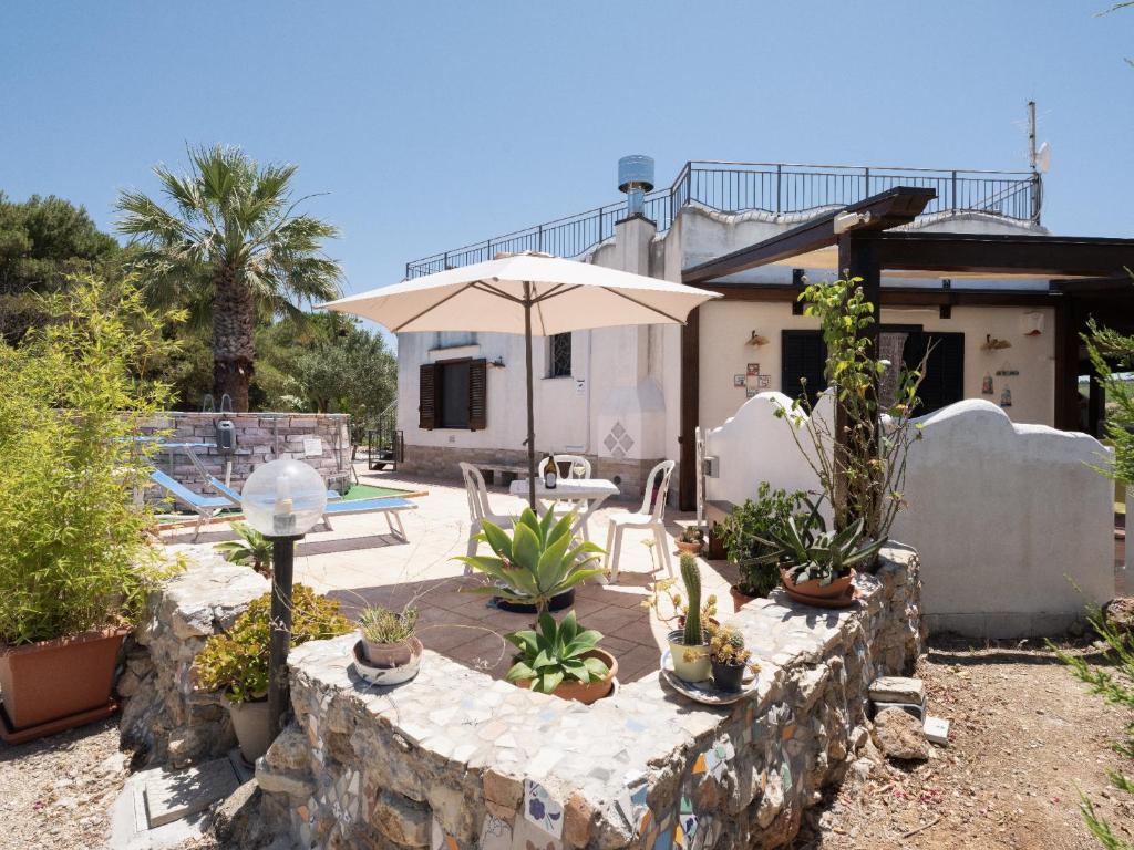 una casa con una pared de piedra y una sombrilla en Casa Vacanze Villa Calathatubi - Locazione turistica breve, en Alcamo Marina