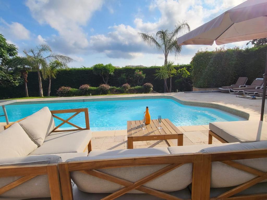 - une piscine avec des chaises, une table et un parasol dans l'établissement Rez-de-Villa 