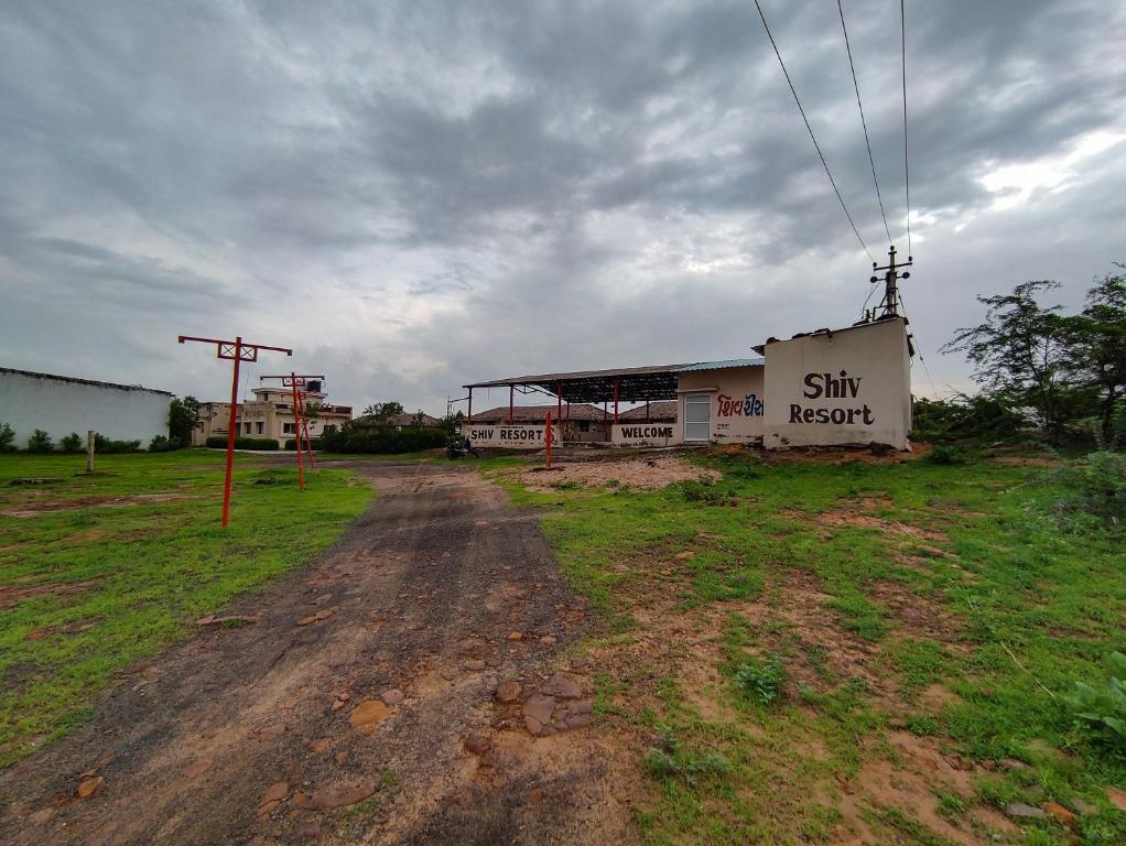 a dirt road in front of a building in a field at River View Resort in Bhuj