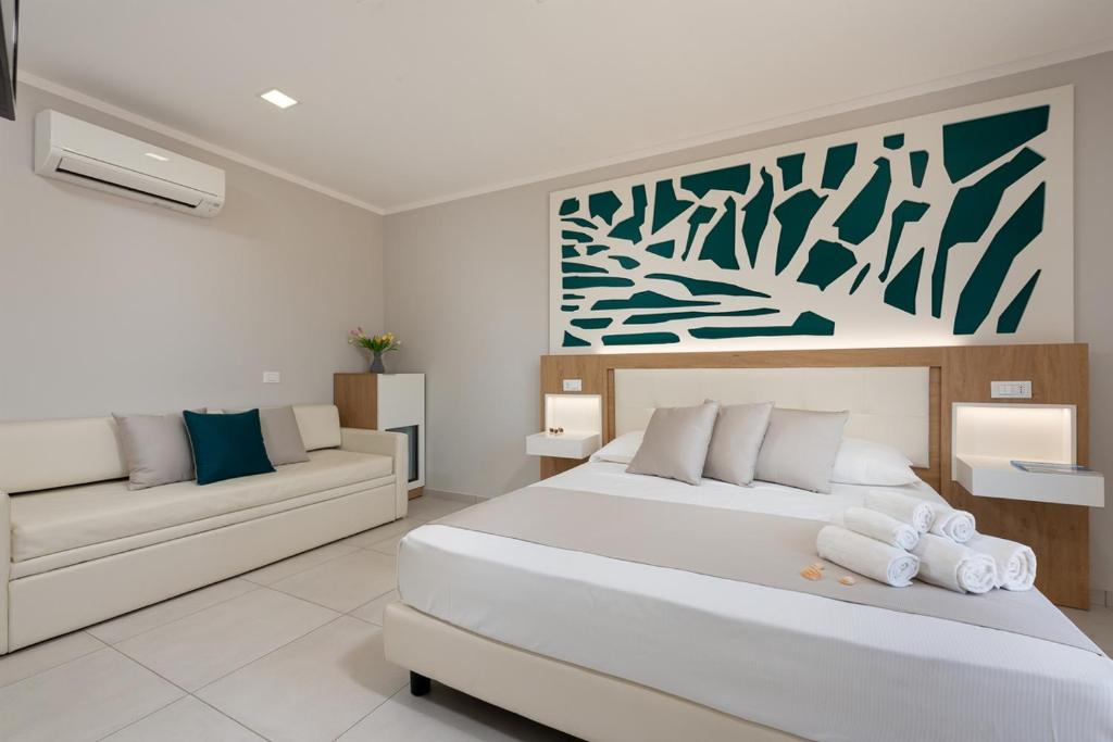 a bedroom with a large bed and a couch at Residence Le Piscine in San Vito lo Capo