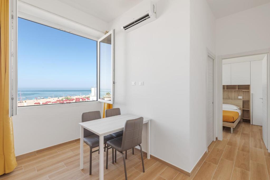 une salle à manger avec une table, des chaises et une grande fenêtre dans l'établissement Residence Torvaianica, à Torvaianica