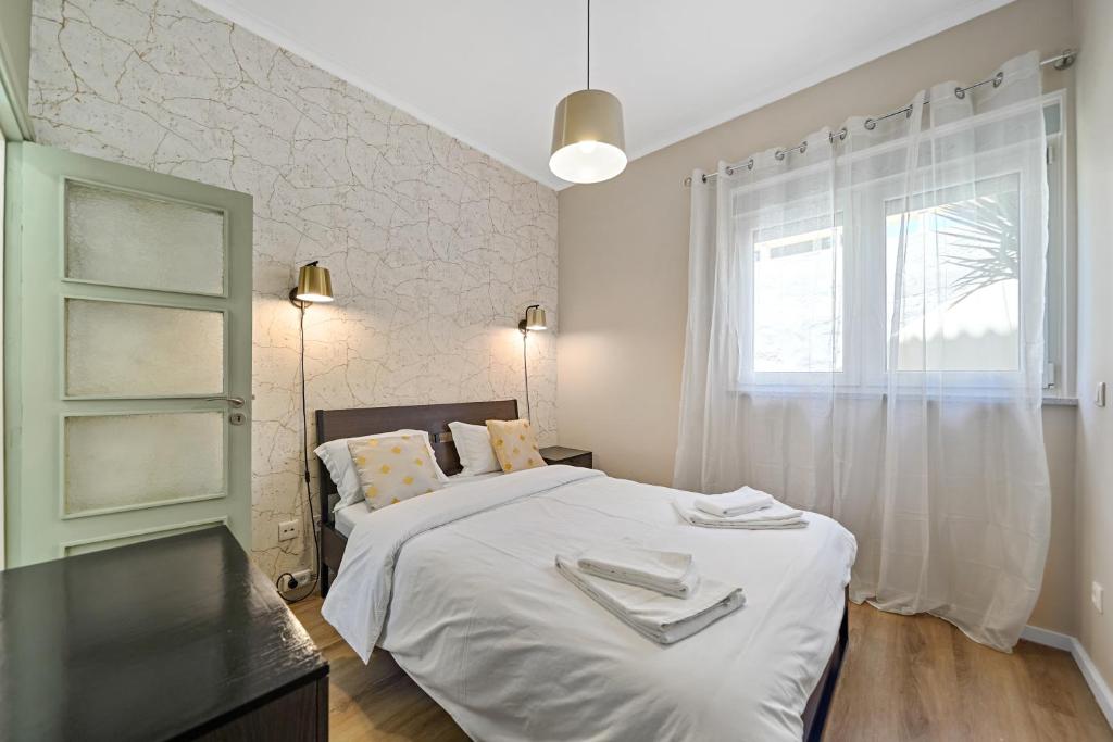 ein Schlafzimmer mit einem Bett mit weißen Laken und einem Fenster in der Unterkunft New Apartments Luiz I Bridge by Amber Star Rent in Vila Nova de Gaia