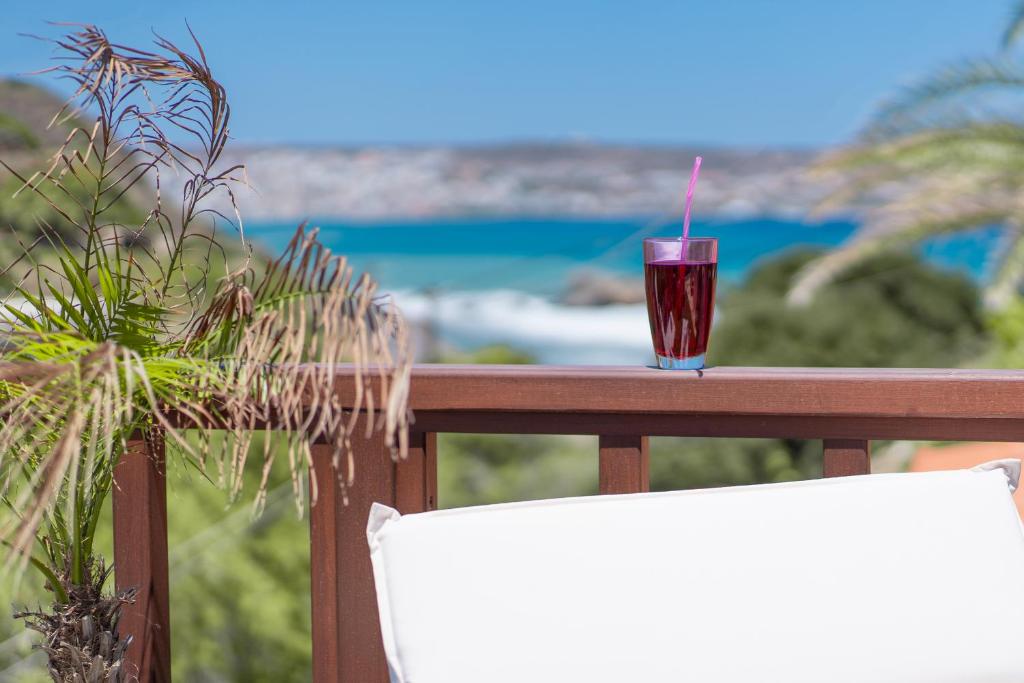 a drink sitting on top of a balcony with the ocean at Rock and Sea View House in Sitia